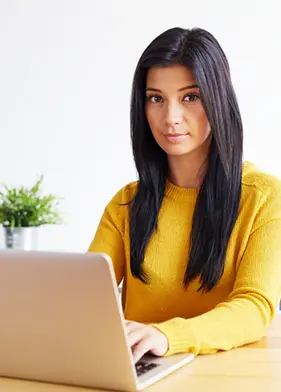 Junge Frau mit dunklem Haar an Laptop sitzend